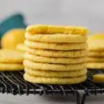 Lemon cookies stacked on wire rack.