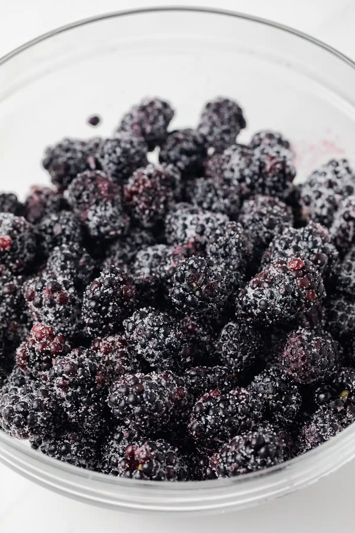 Blackberries coated in sugar in glass bowl.