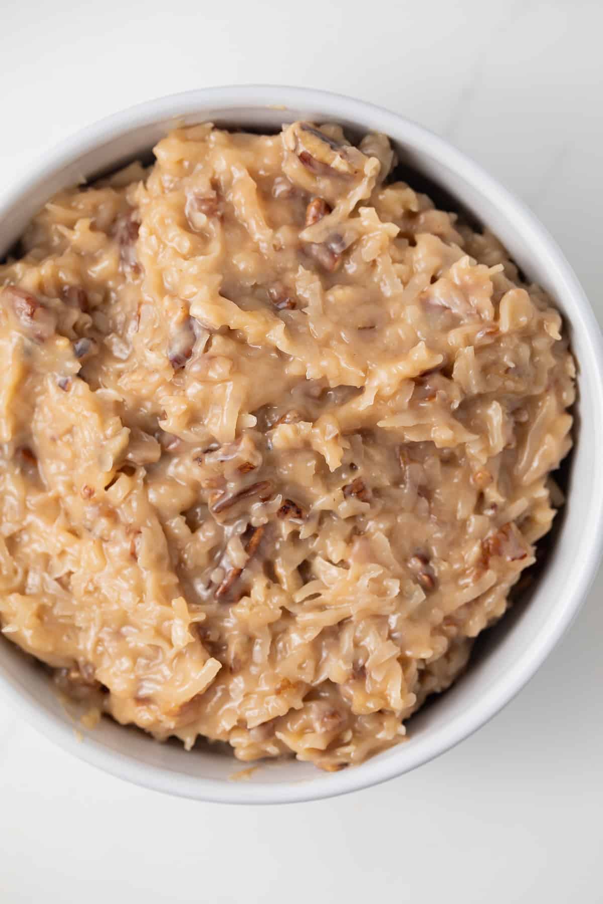 Close up of German chocolate cake frosting in white bowl.