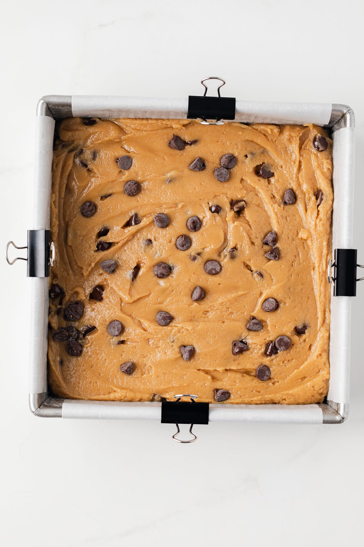 Unbaked peanut butter chocolate chip blondies in square baking pan.