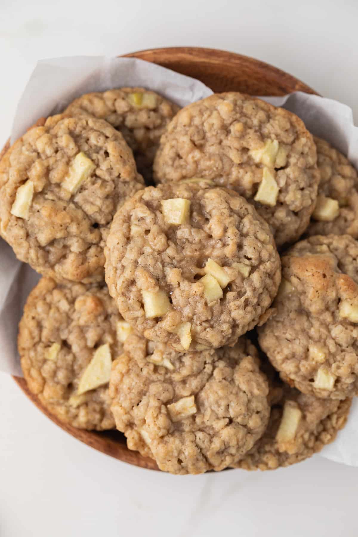 Apple oatmeal cookies on a serving platter with parchment paper.