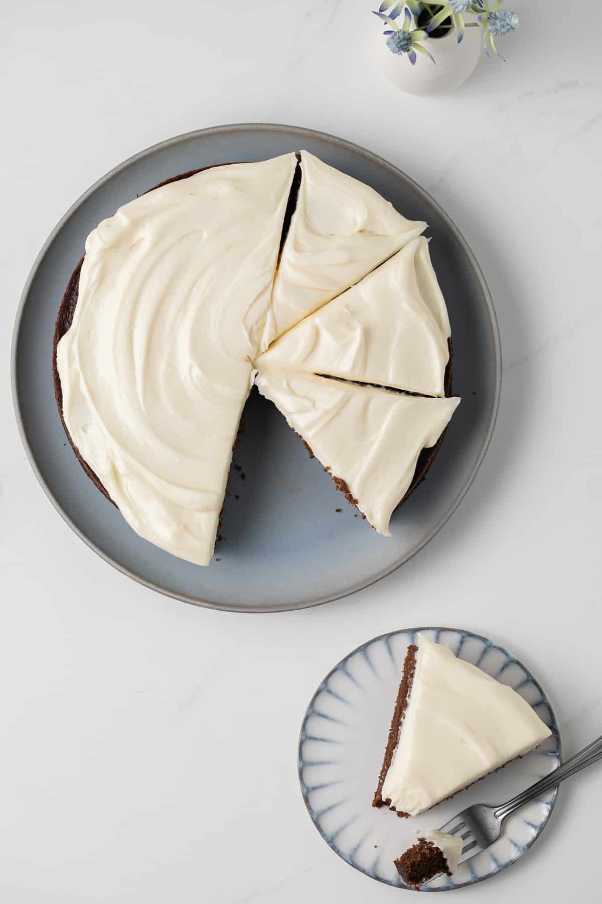 Overhead of sliced gingerbread cake topped with cream cheese frosting.