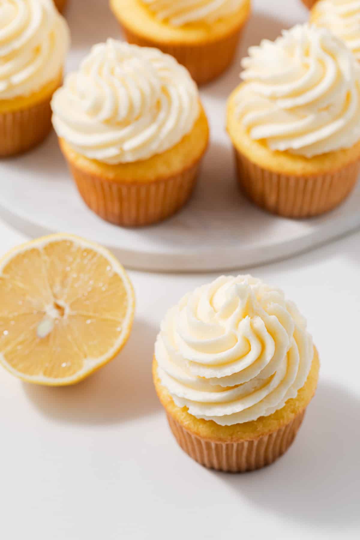 Angled view of cupcakes topped with lemon buttercream frosting.