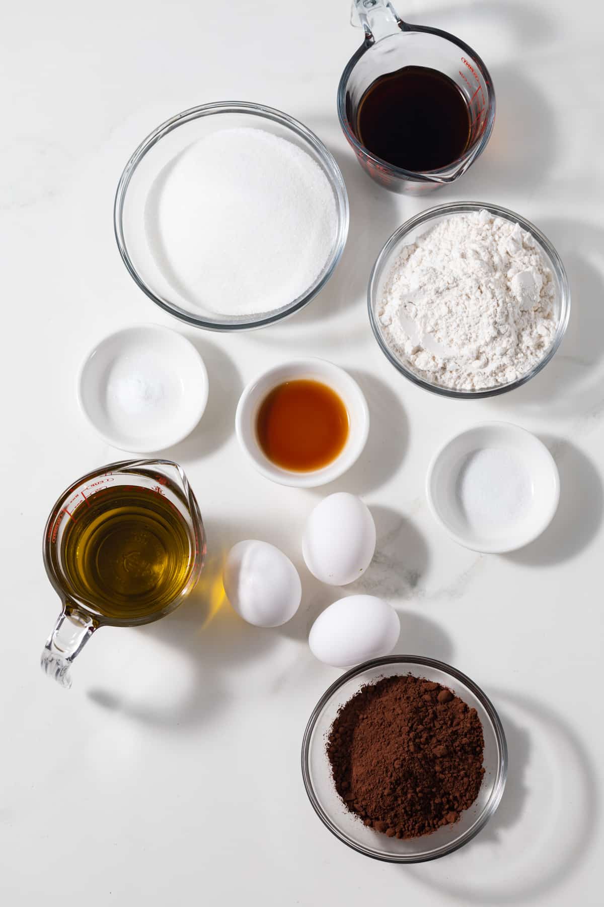 Ingredients for chocolate olive oil cake in glass bowls.