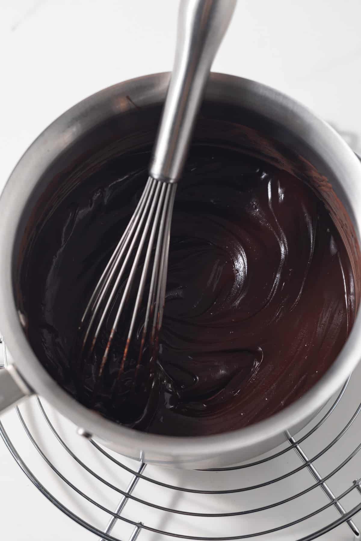 Chocolate paste in saucepan with whisk.