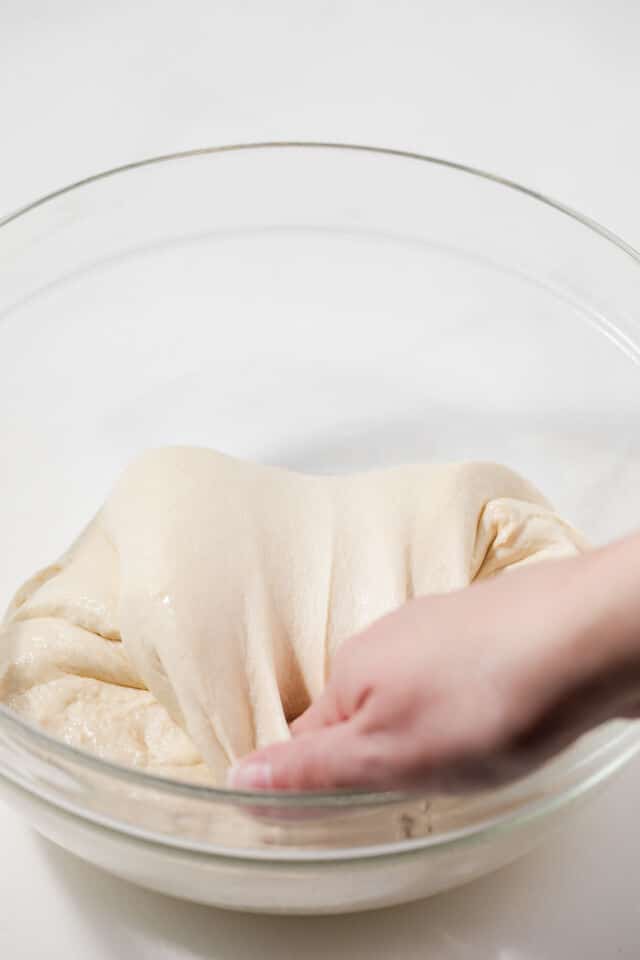 Stretch and fold dough in glass bowl.