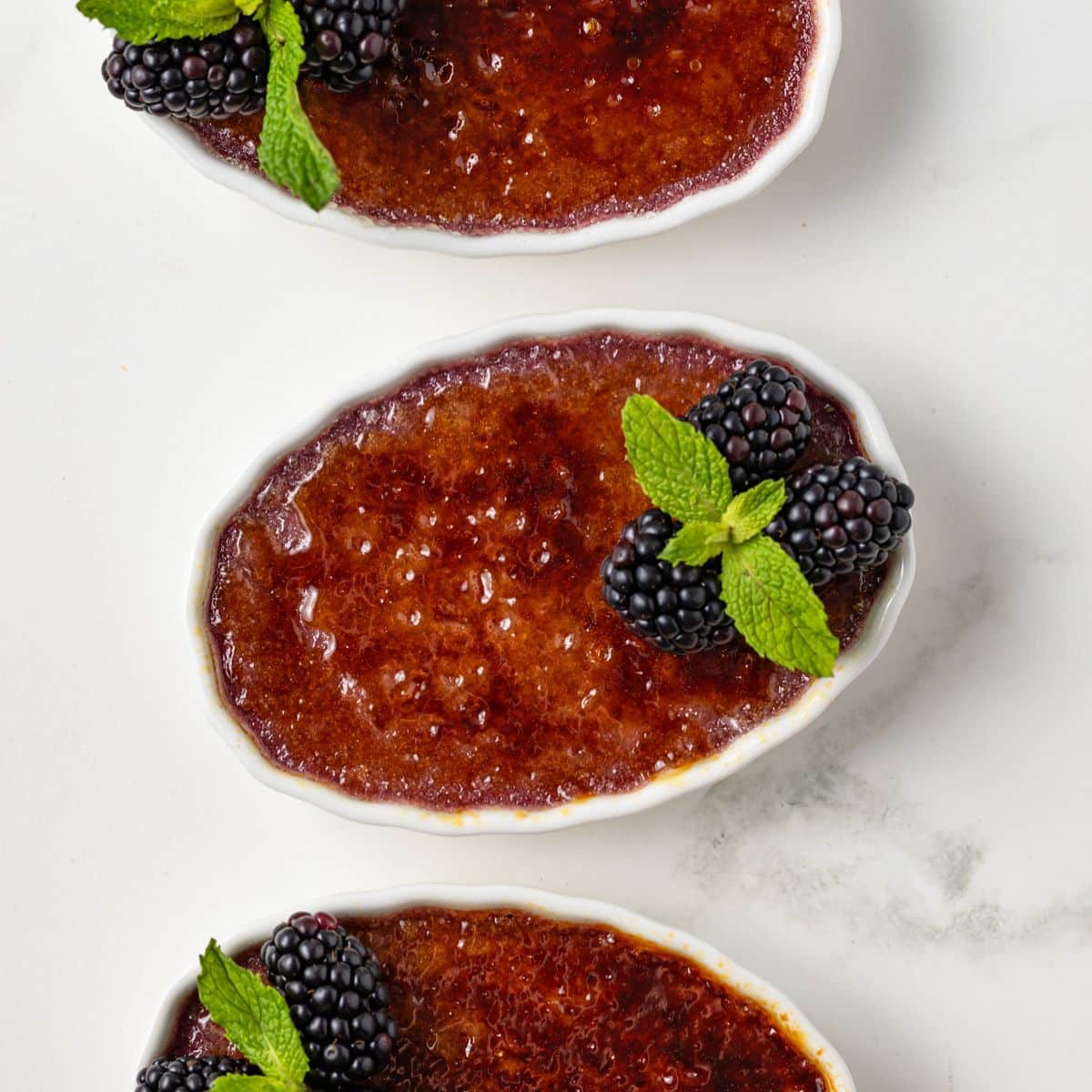 Three ramekins of blackberry creme brulee.