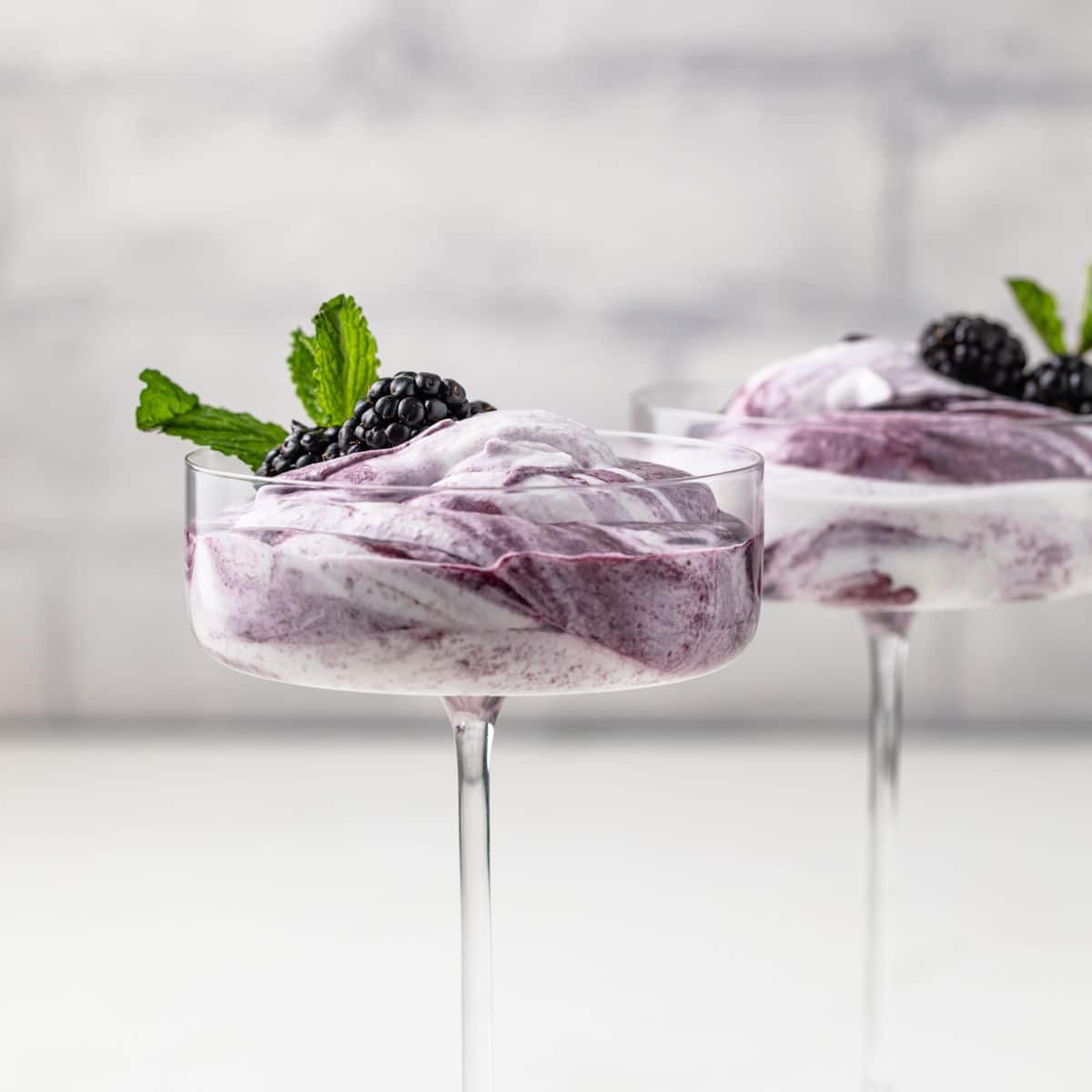 Side view of blackberry fool in glass cup.