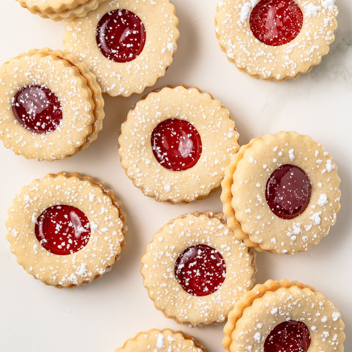 Strawberry linzer cookies spread on white background.