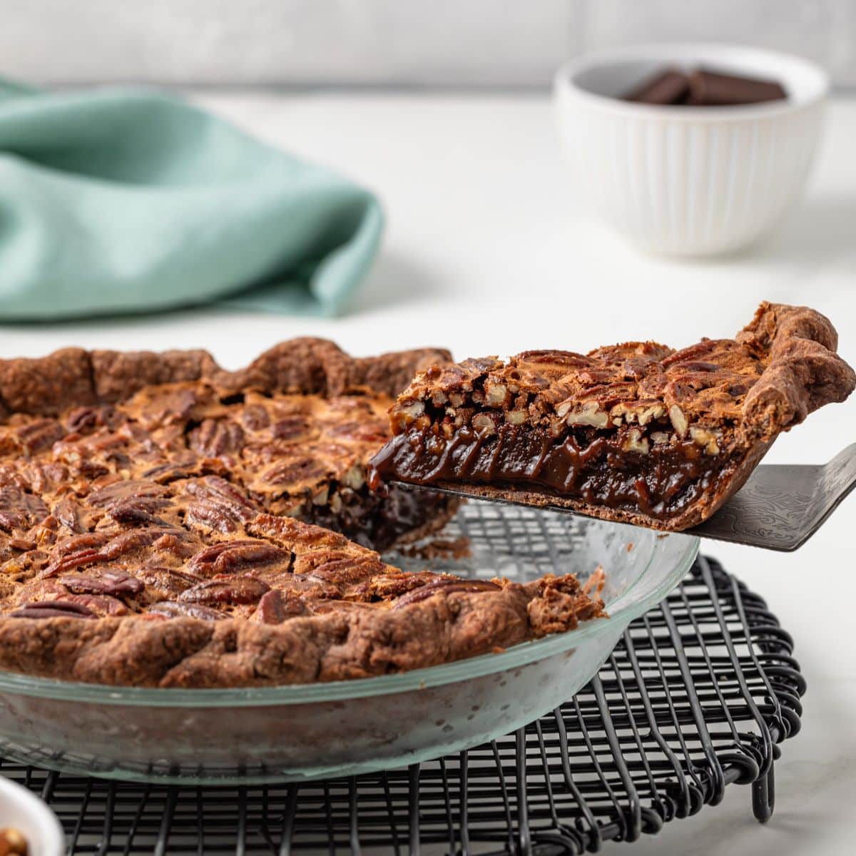 Slice of chocolate pecan pie lifted out of whole pie.