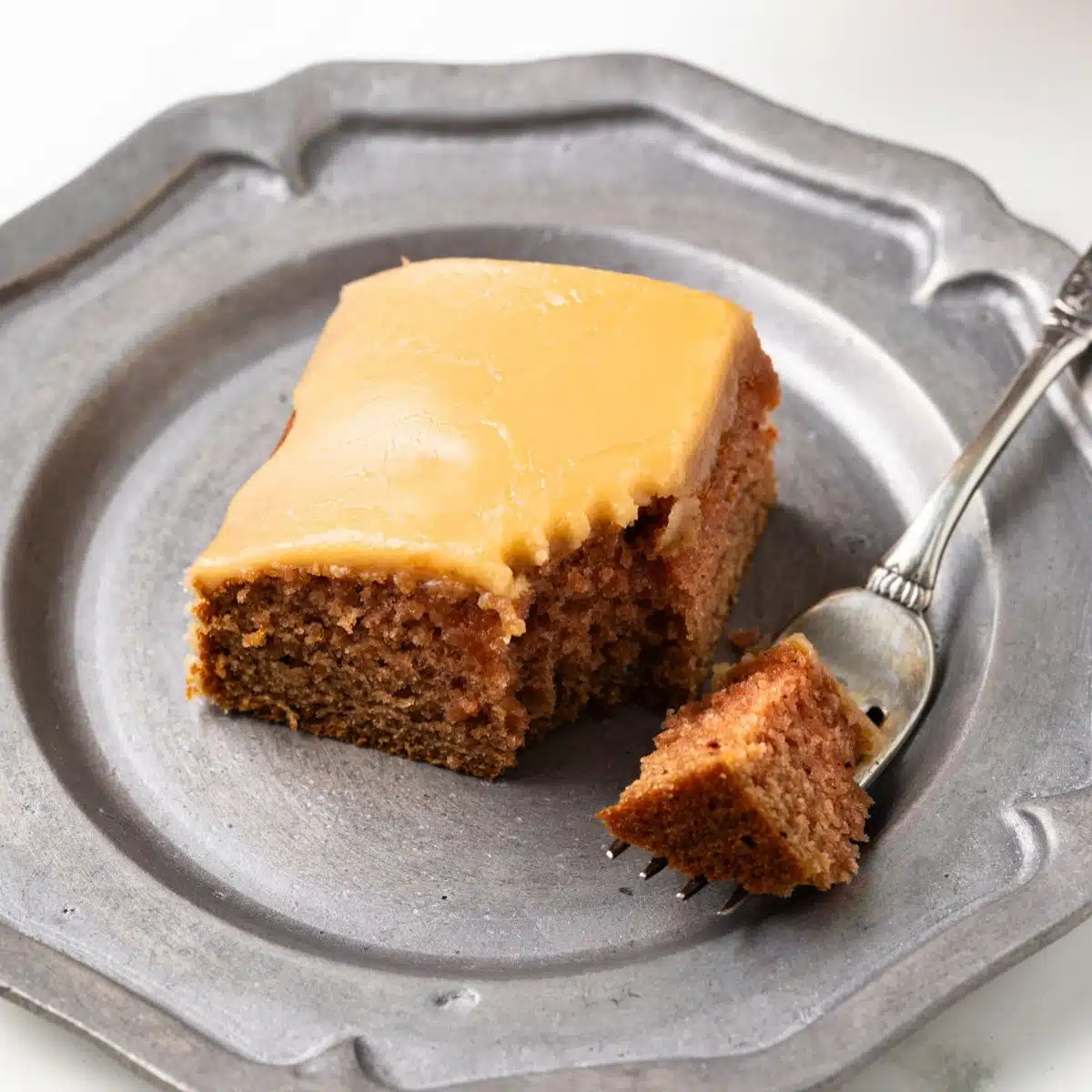 Bite taken out of slice of applesauce cake.