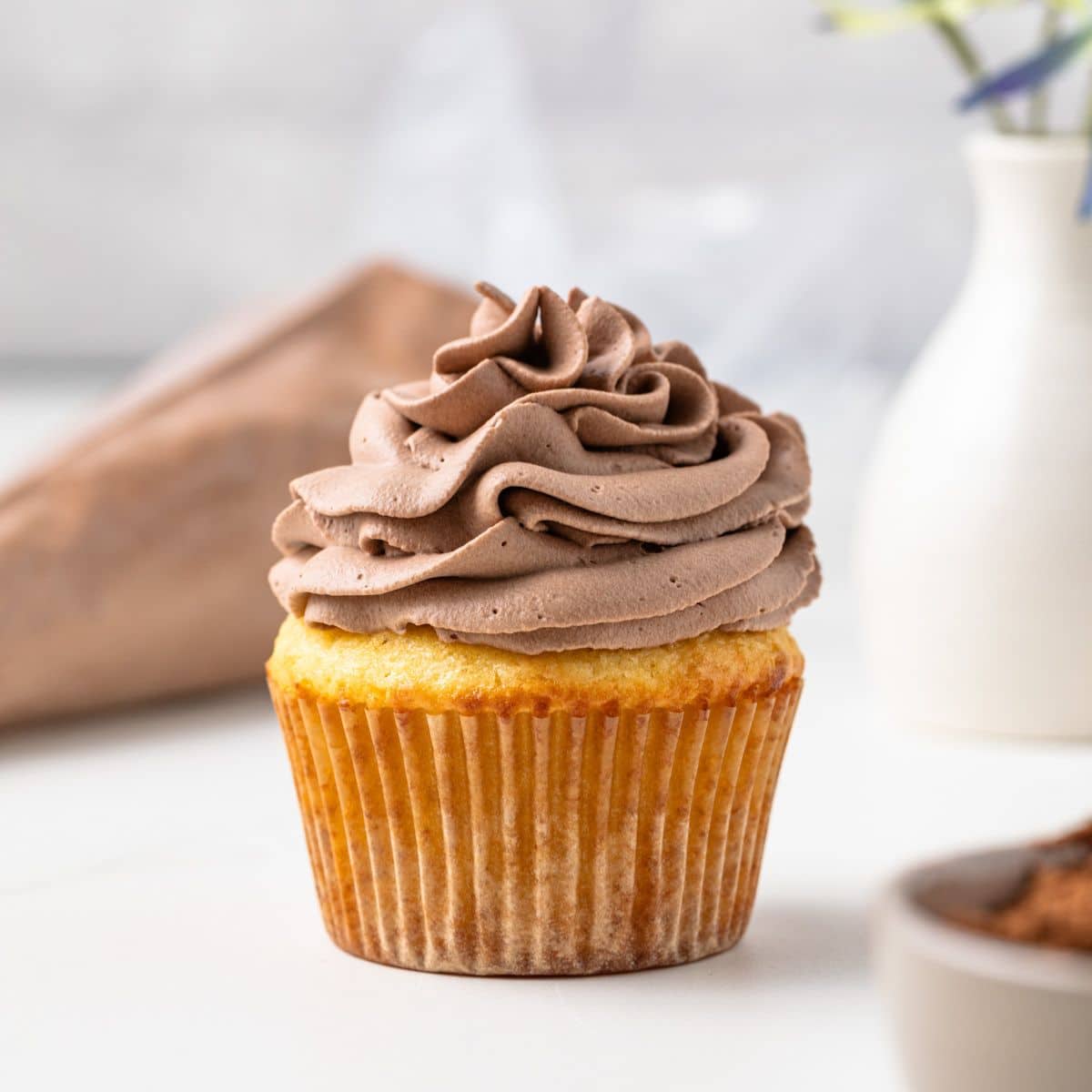 Chocolate whipped cream swirled on a vanilla cupcake.