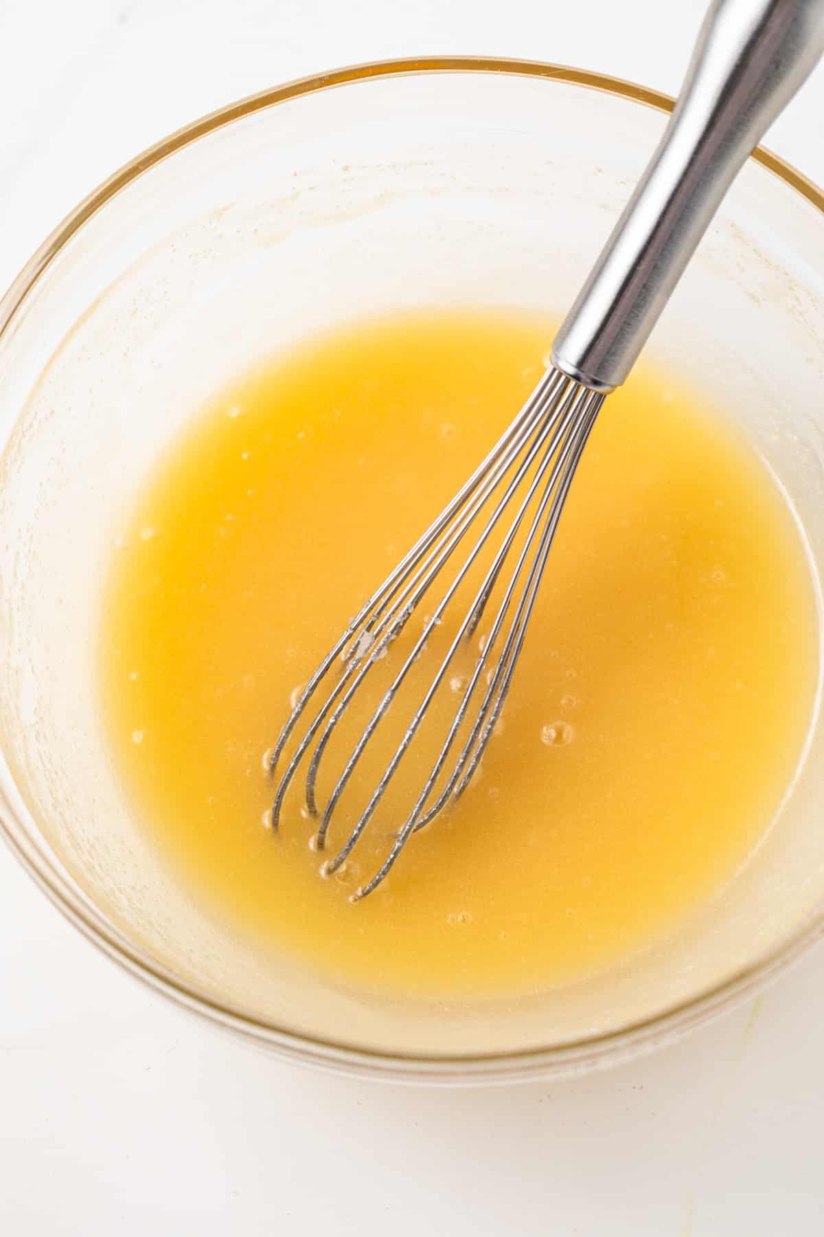 Melted butter and sugar mixed in glass bowl.