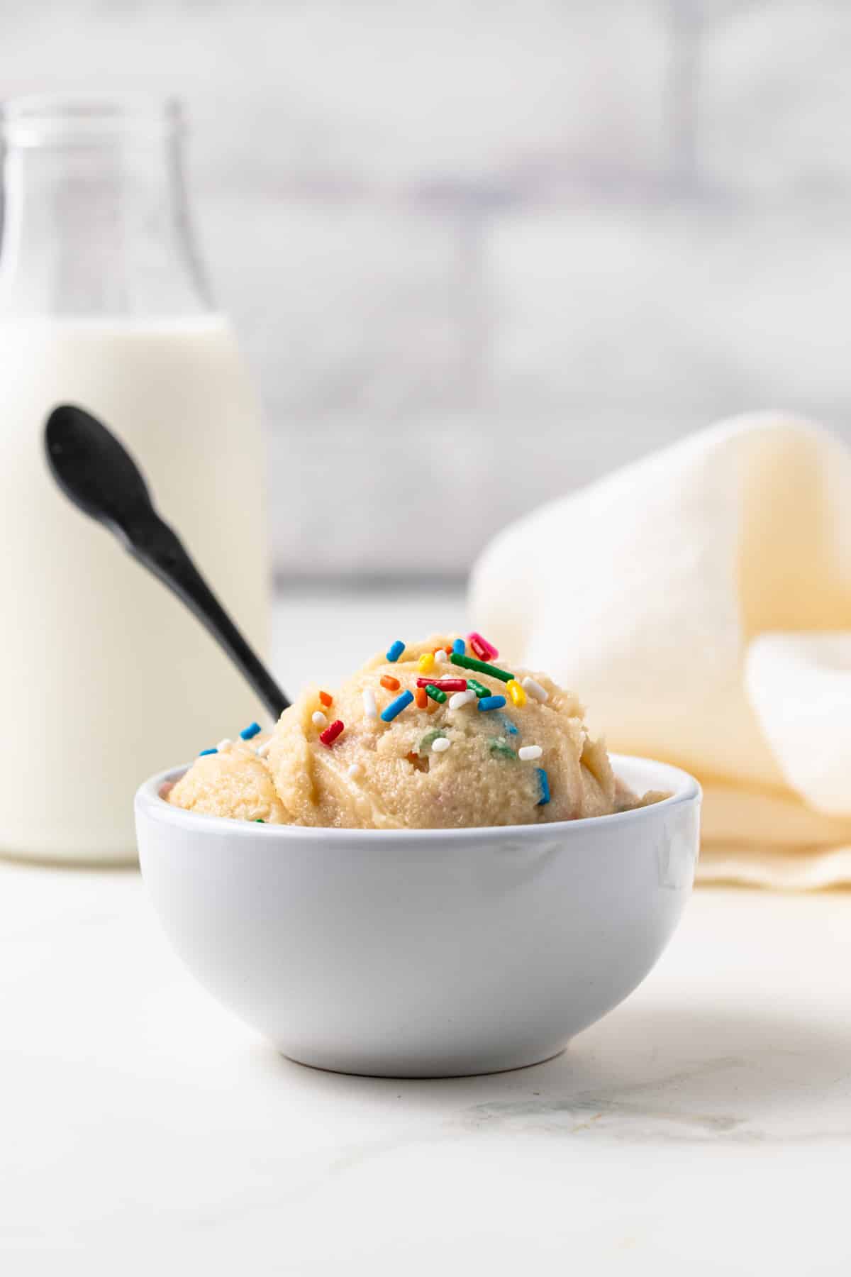 Side view of edible cookie dough in white bowl.