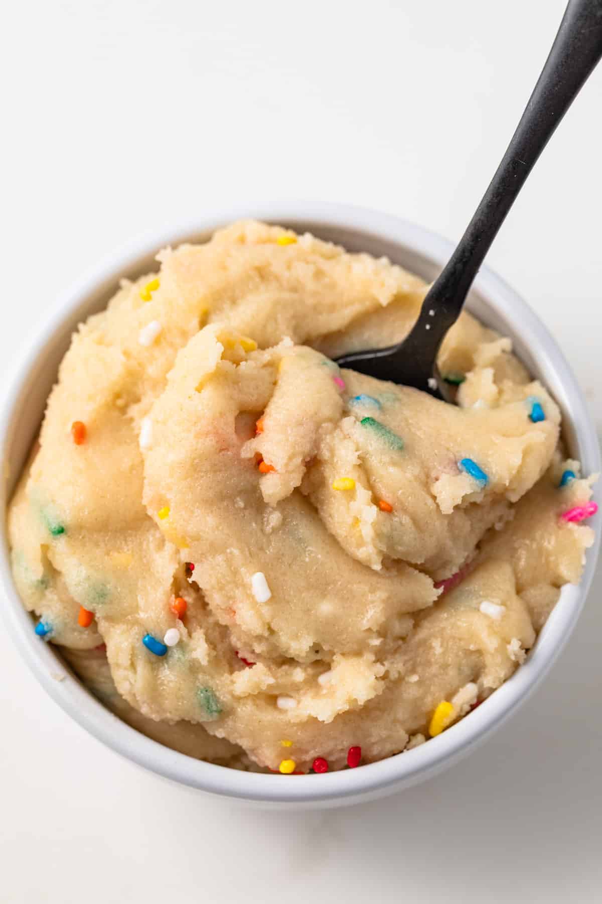Close up of edible sugar cookie dough in a white bowl.