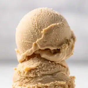 Two scoops of peanut butter ice cream on a cone.
