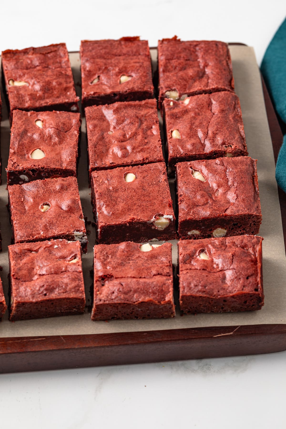 Angled view of red velvet brownies on wooden board.