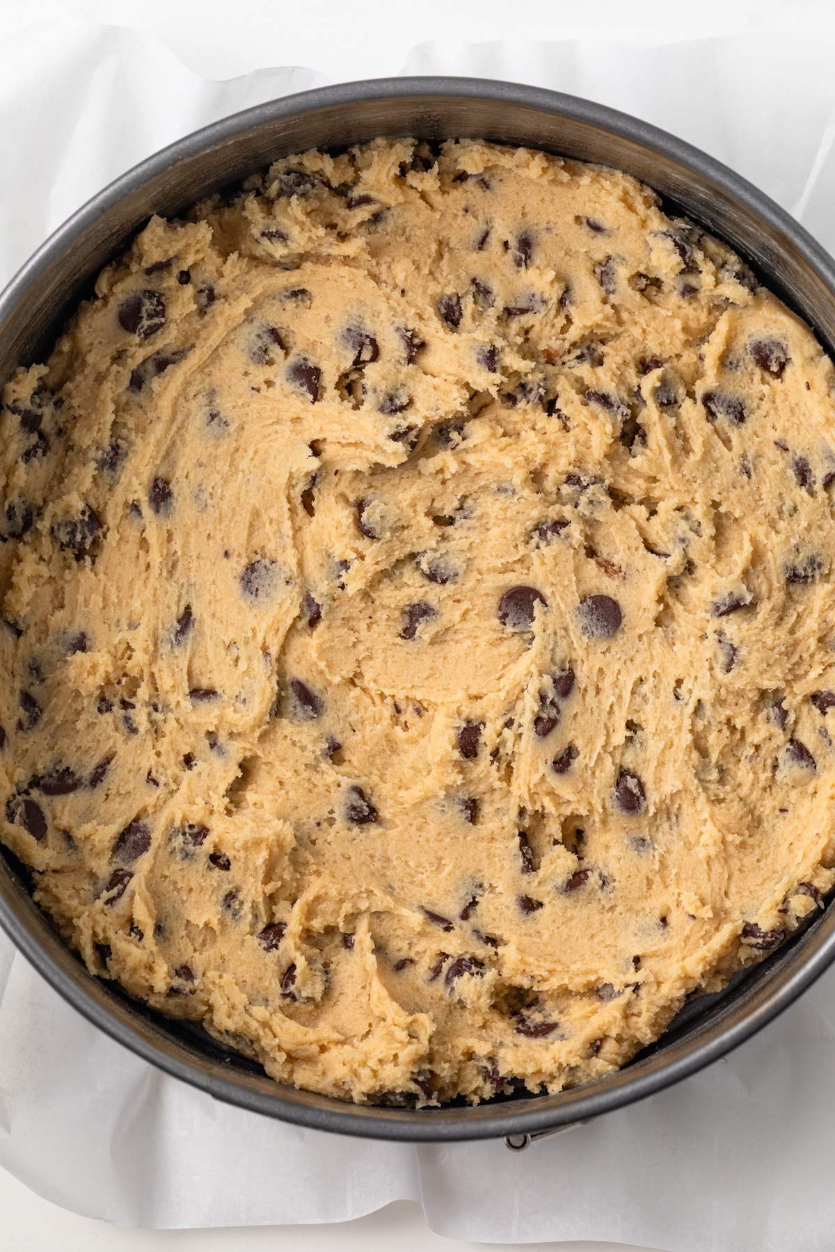 Chocolate chip cookie dough in a springform pan.