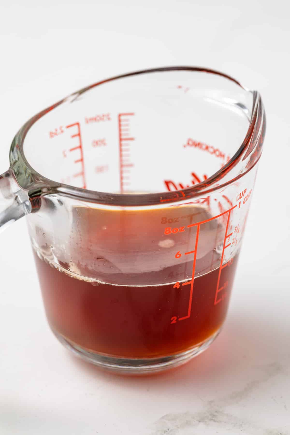 Apple cider reduction in liquid measuring cup.