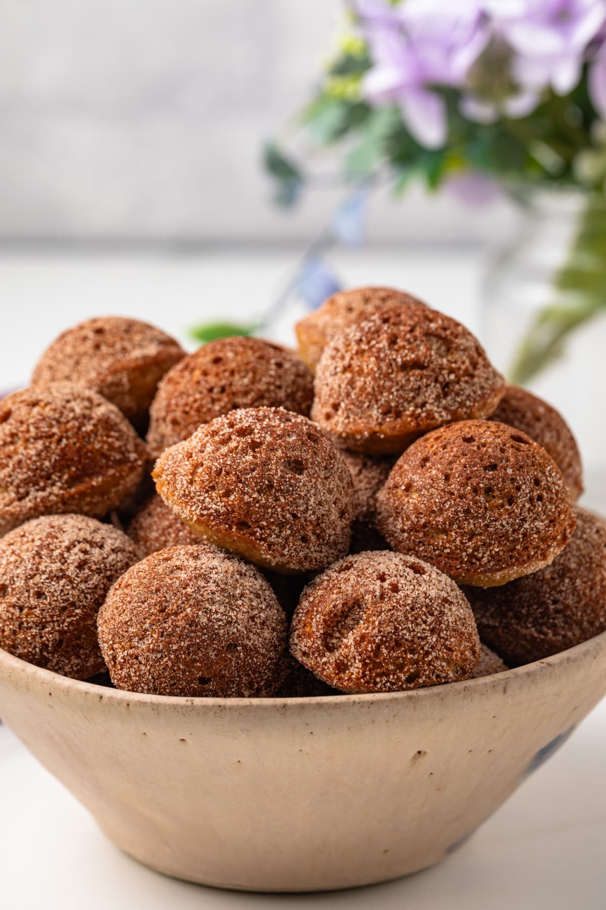 Side view of baked apple cider donut holes in bowl.