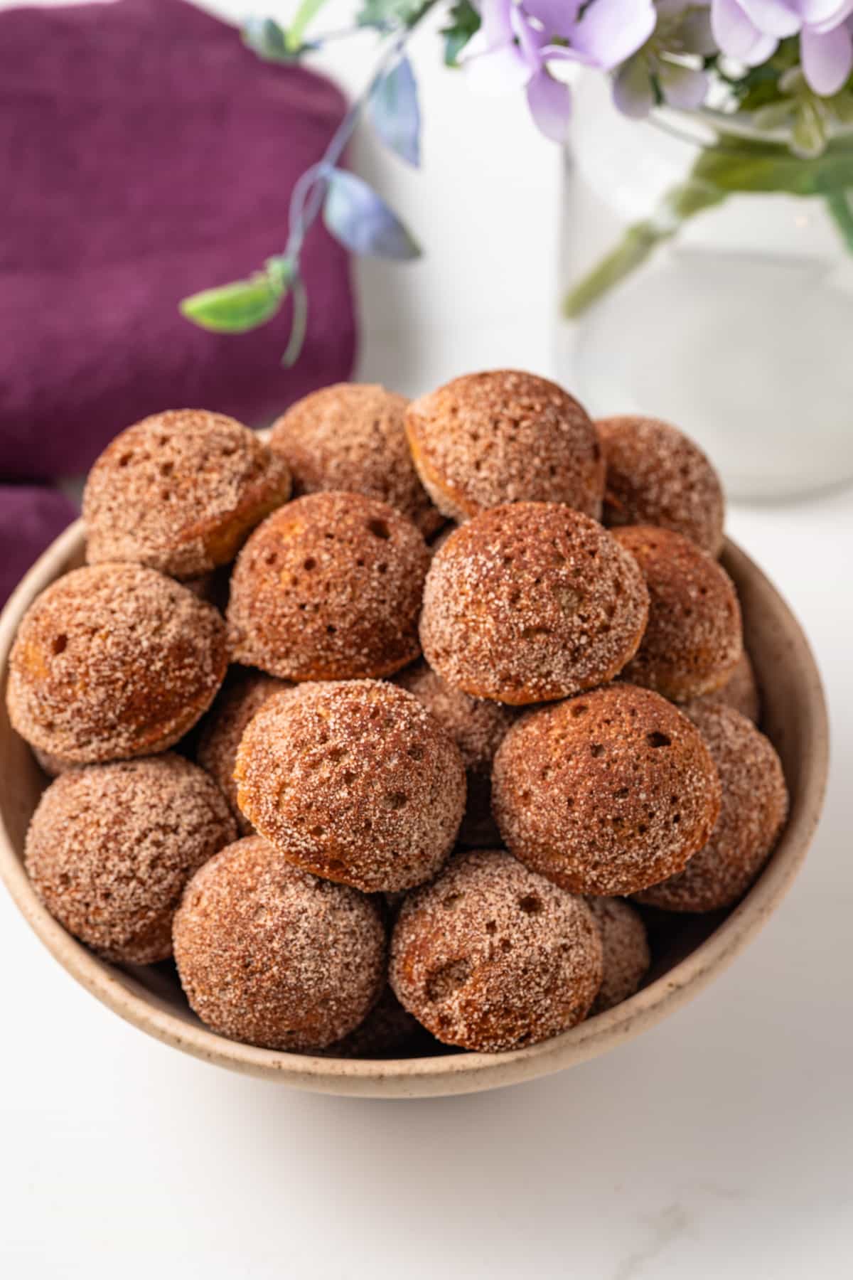 Angled view of apple cider donut holes in bowl.