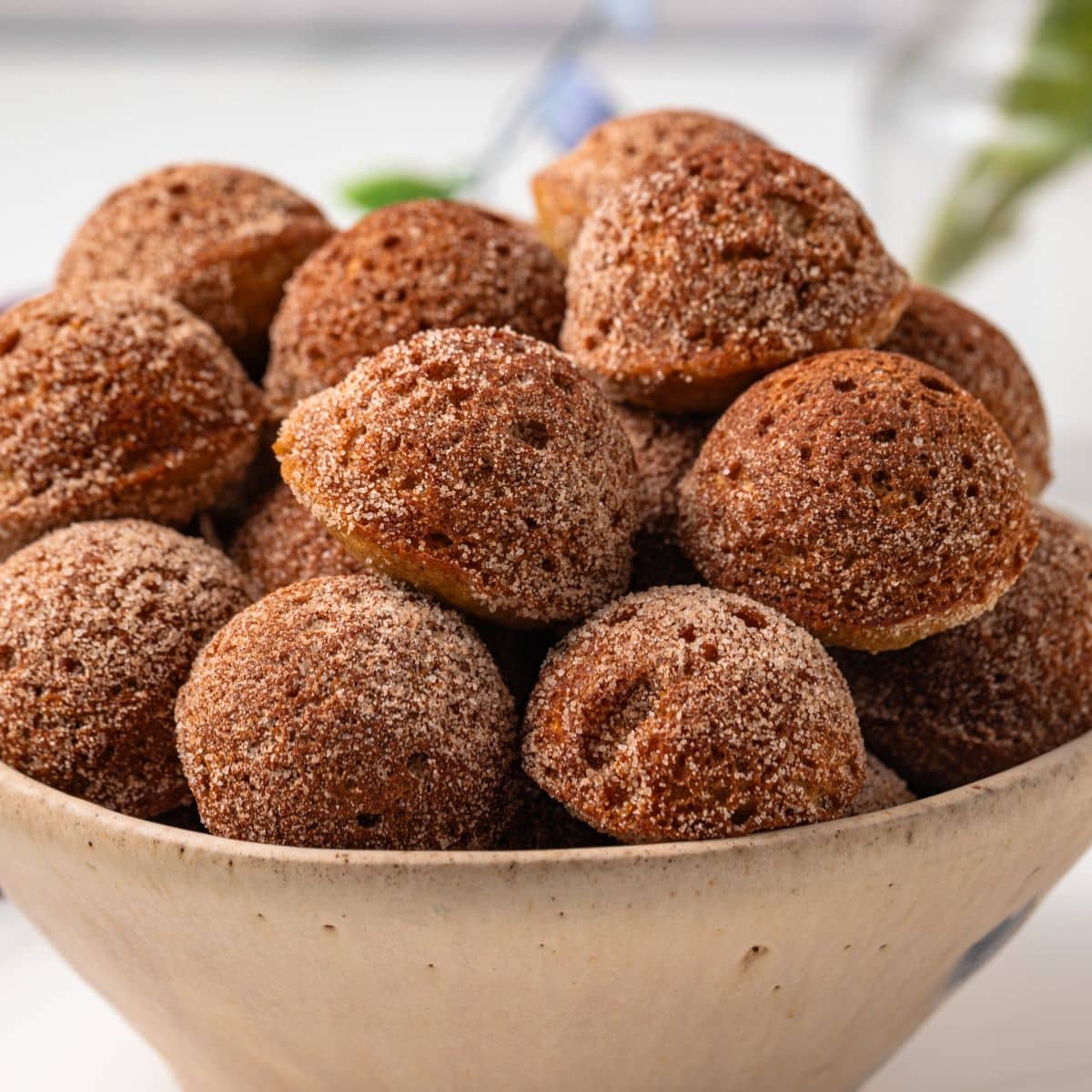 Side view of baked apple cider donut holes in bowl.