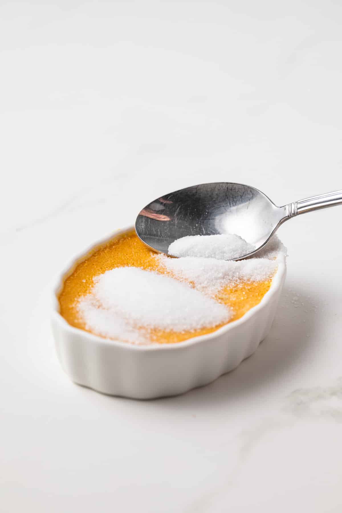 Sugar being poured over baked creme brulee.