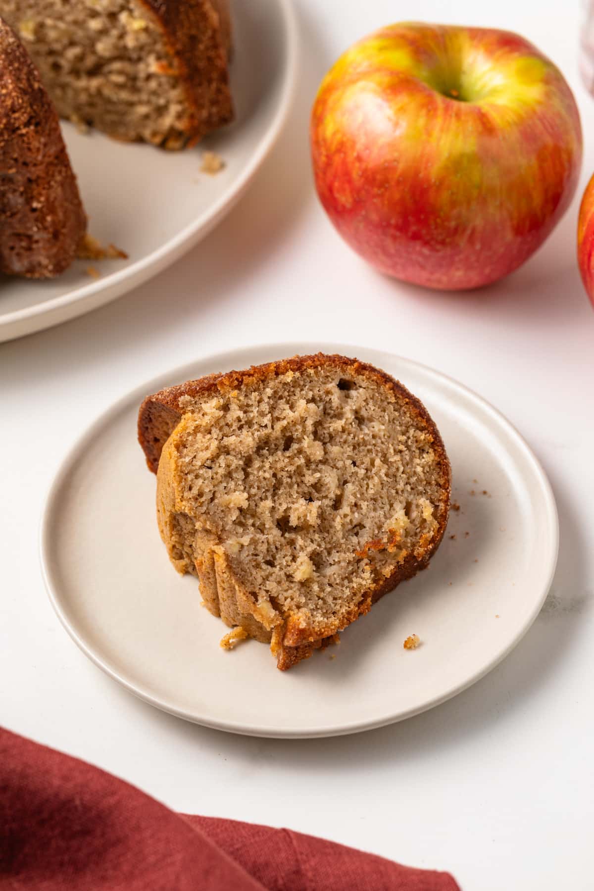 Slice of apple cider donut cake on white plate.