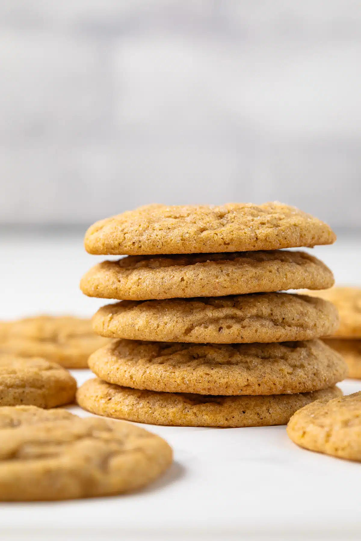 Pumpkin cookies stacked on parchment paper.