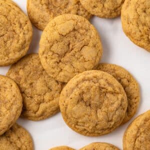 Pumpkin sugar cookies scattered on parchment paper.