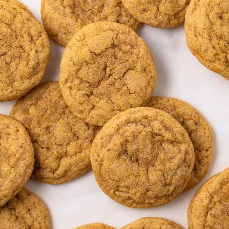 Pumpkin sugar cookies scattered on parchment paper.