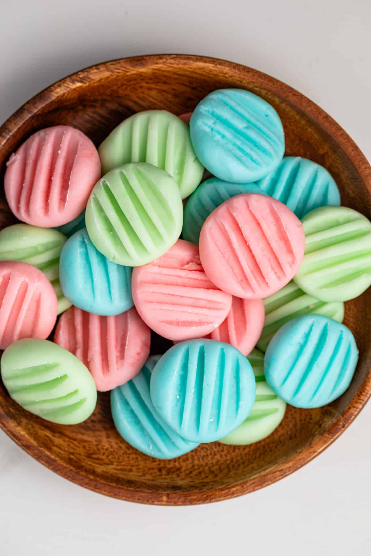 Close up of cream cheese mints in a brown bowl.