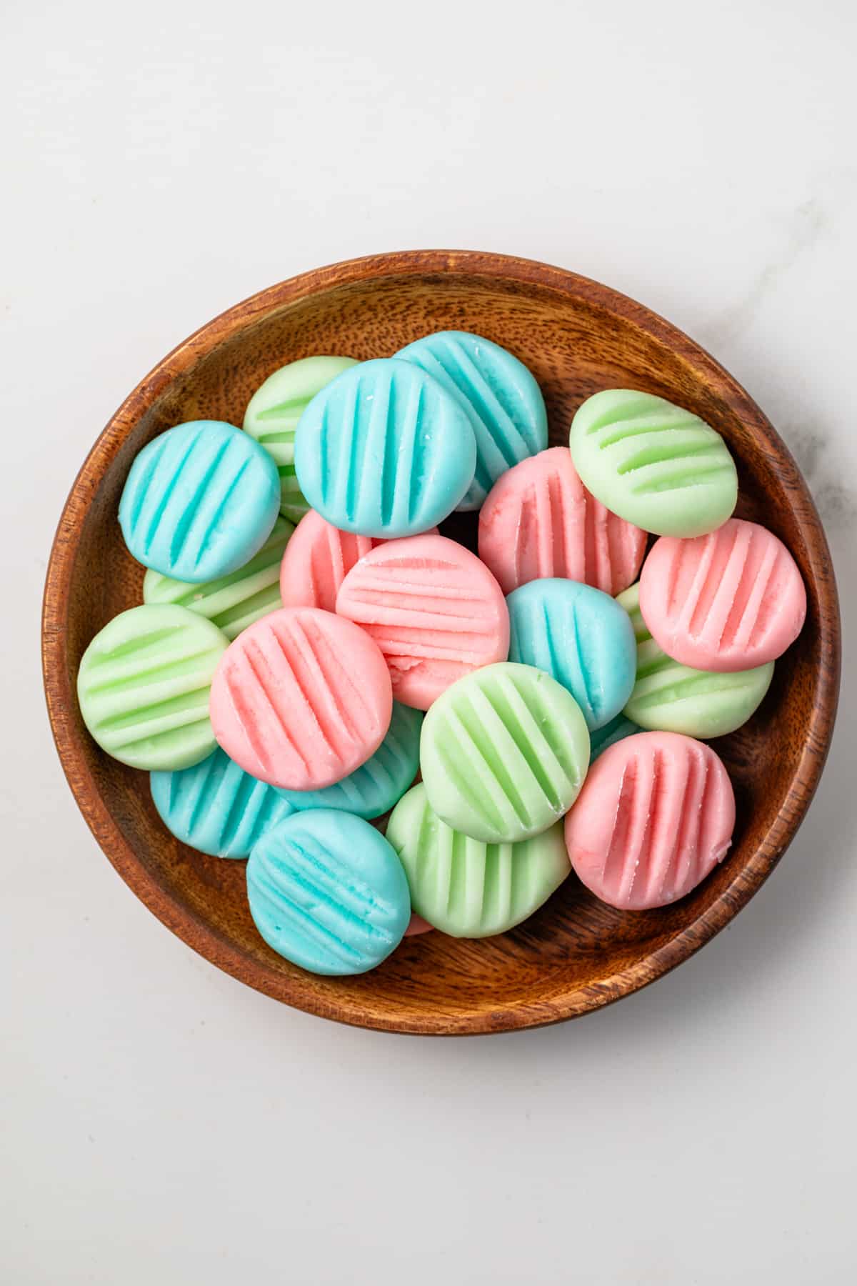 Overhead of cream cheese mints in a brown bowl.