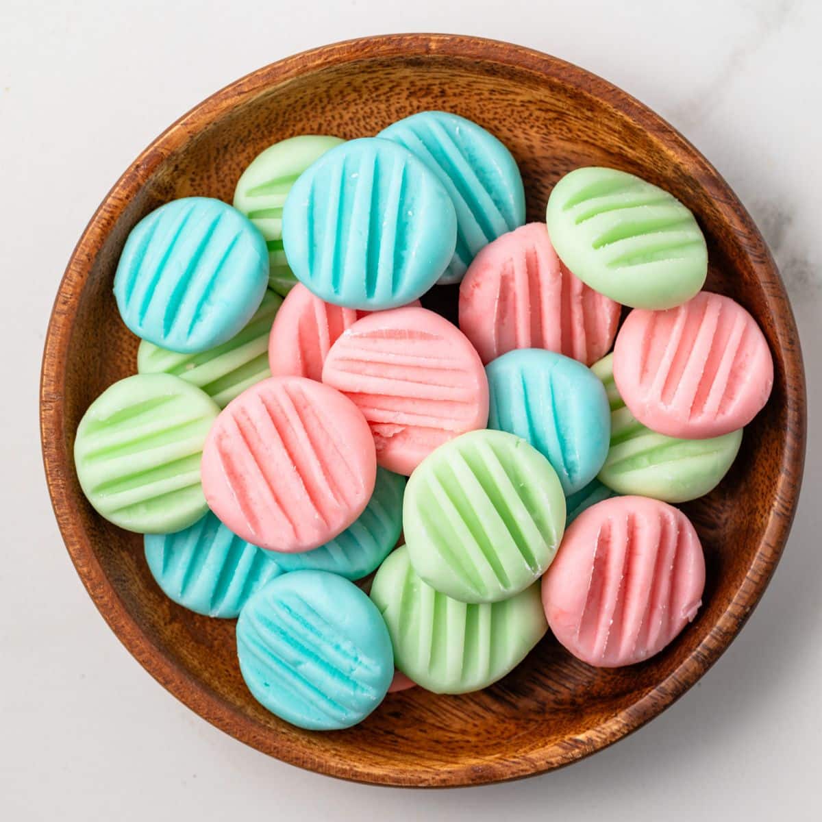 Overhead of cream cheese mints in a brown bowl.