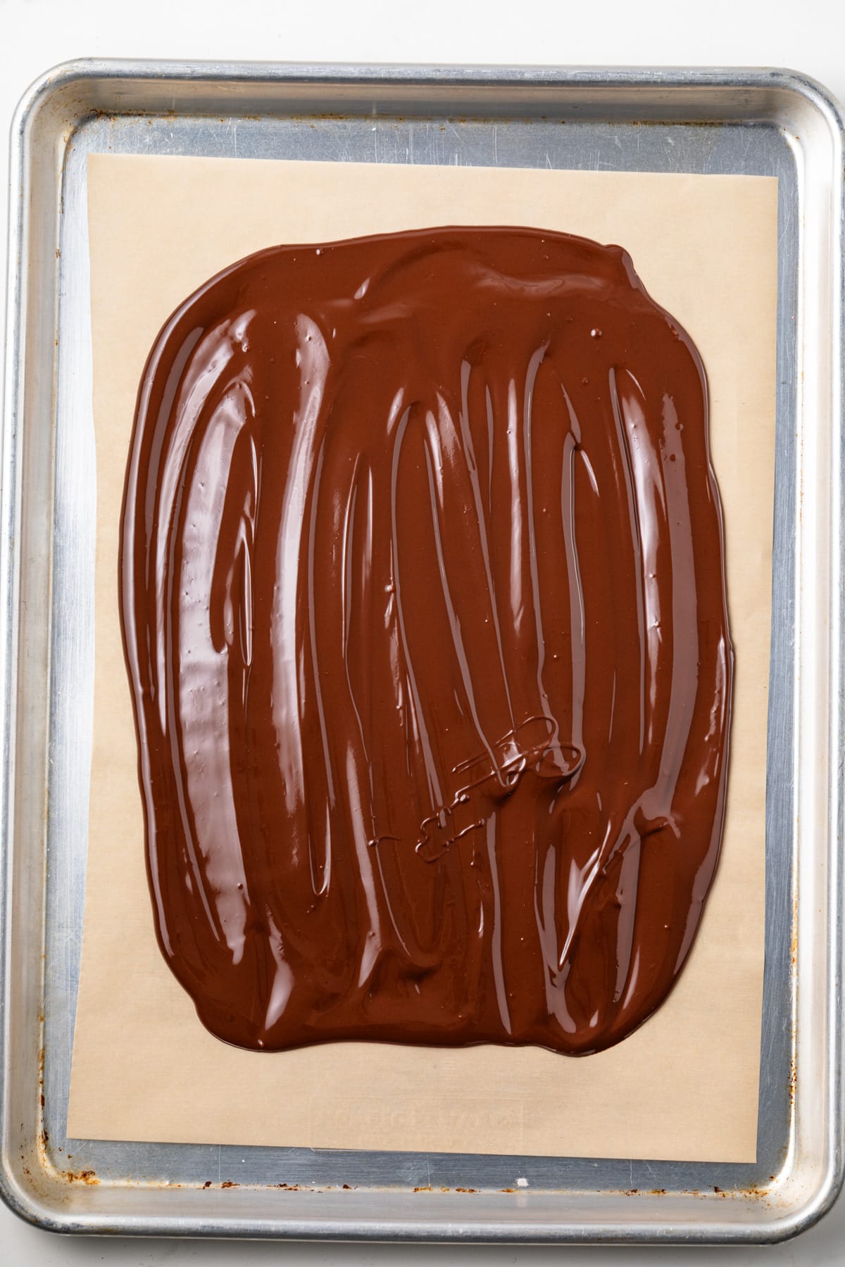 Melted chocolate spread over parchment paper.