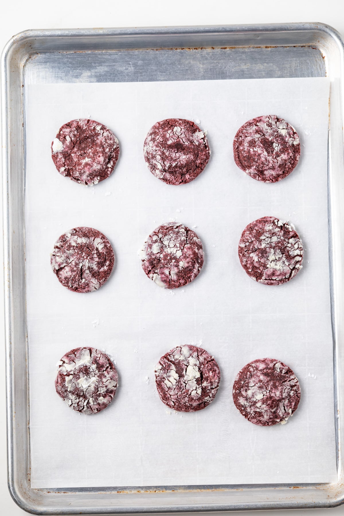 Red velvet crinkle cookies on a baking sheet.