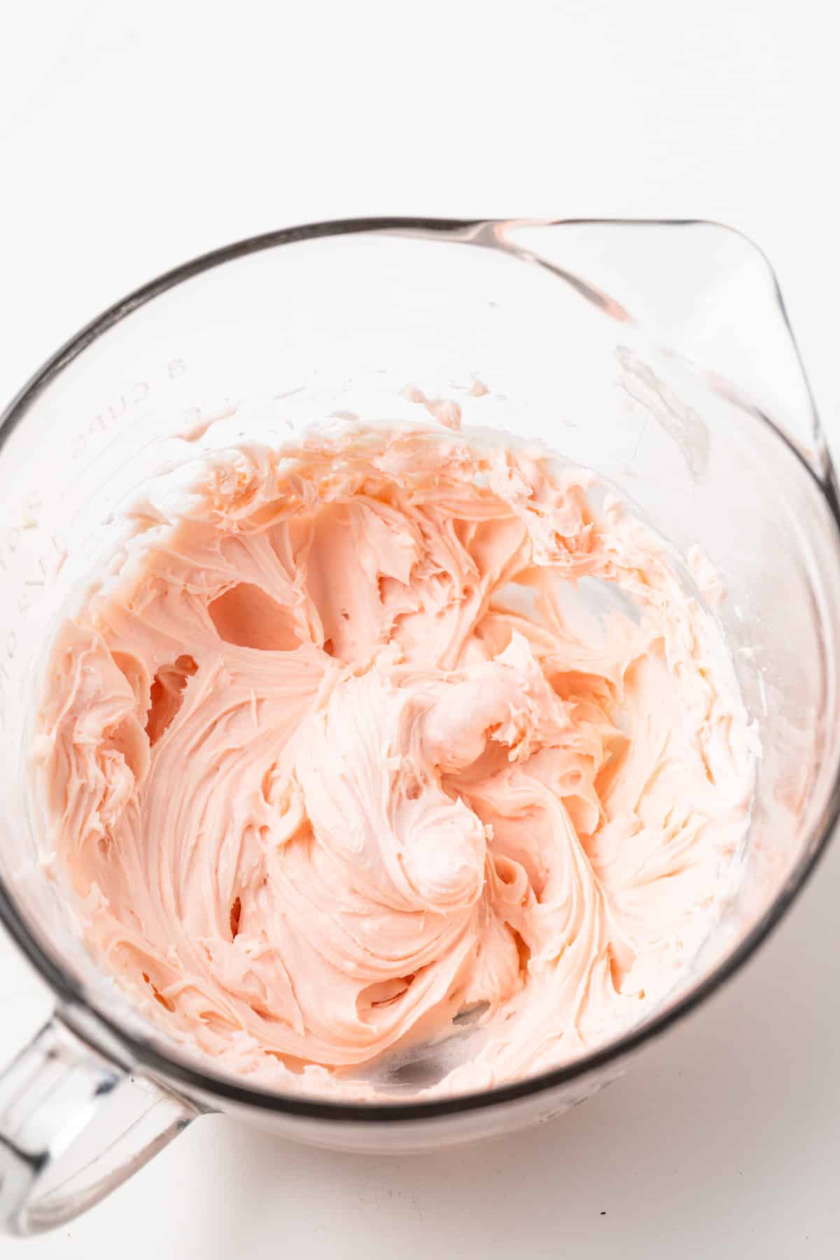 Pink cookie frosting in a glass bowl.