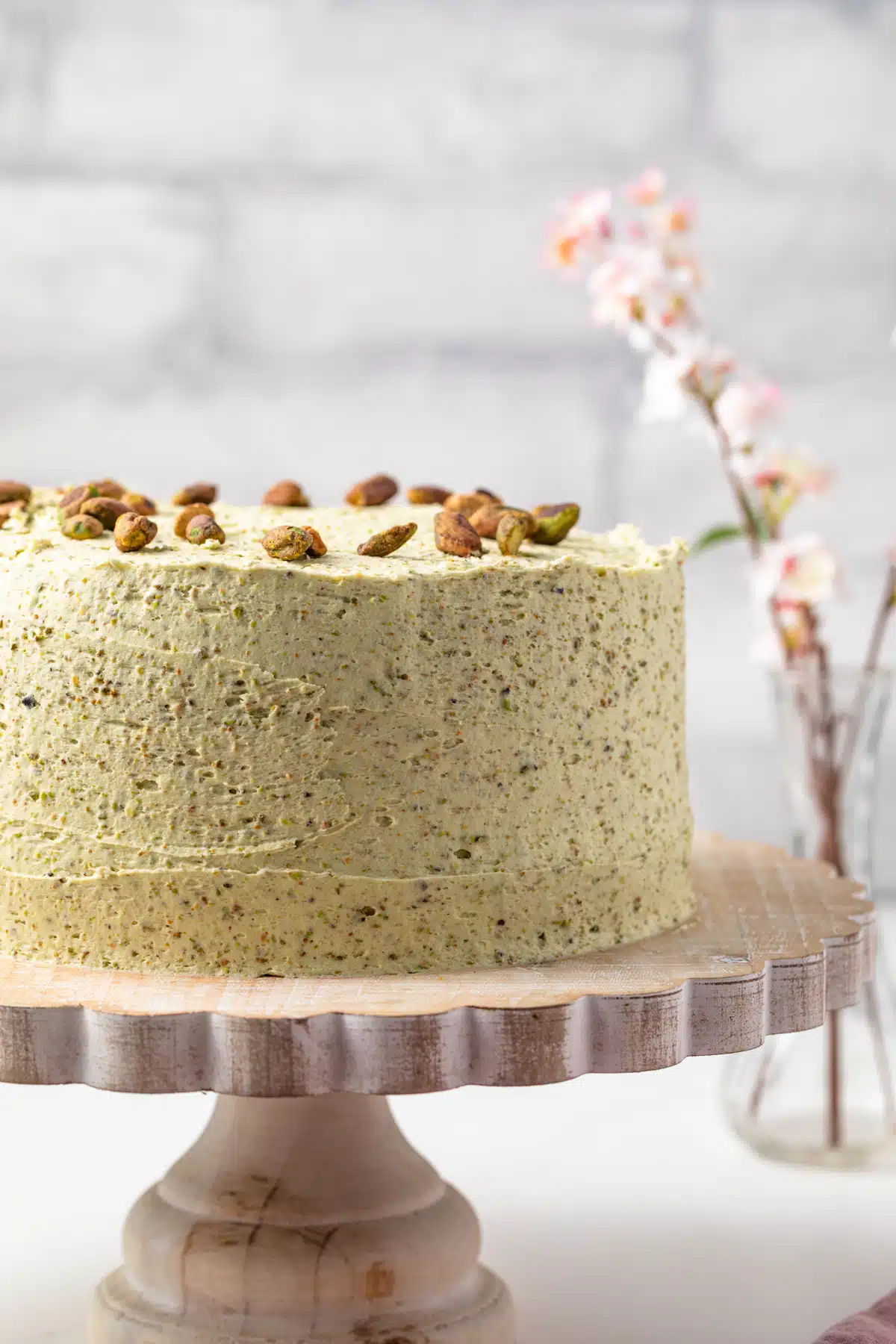 Side view of pistachio cake on a cake stand.