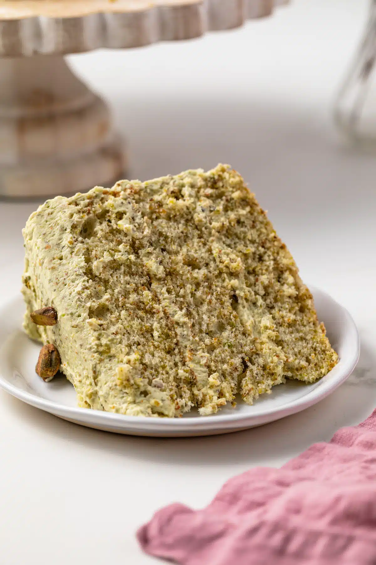 Slice of pistachio cake on a white plate.