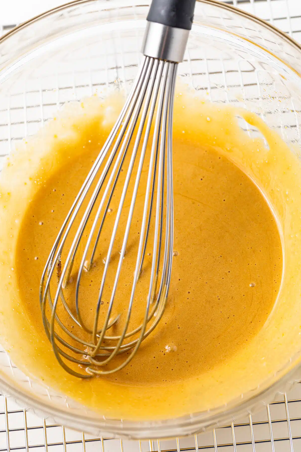 Egg yolks and sugar mixed in a glass bowl.
