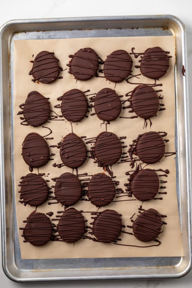 Chocolate dipped peanut butter eggs on a baking tray.