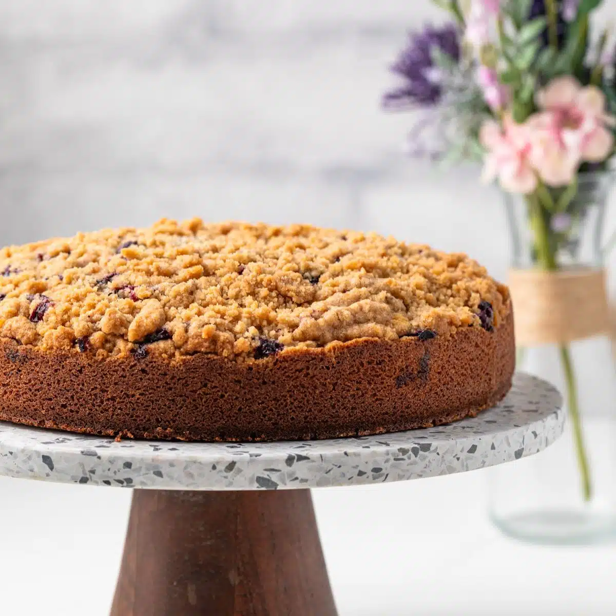 Side view of blueberry coffee cake on a cake stand.