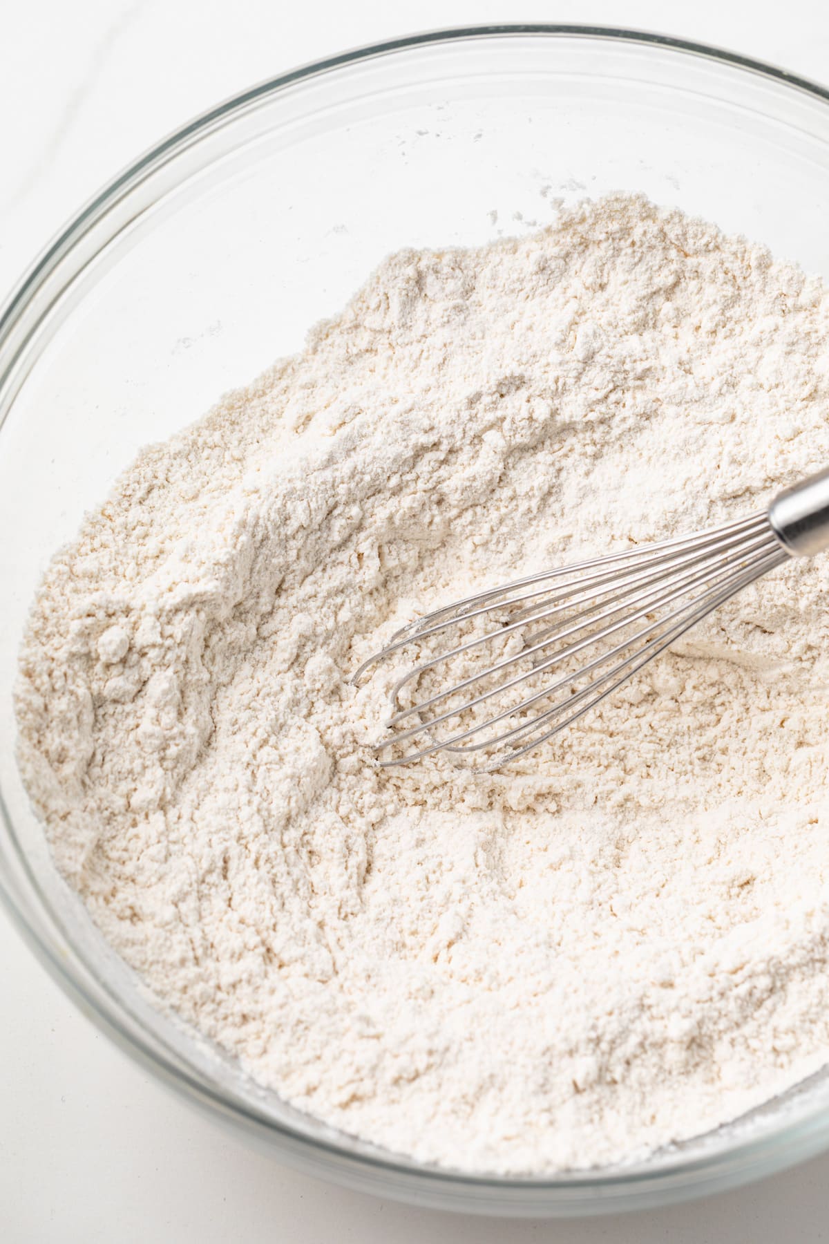 Flour in a glass bowl with a whisk.