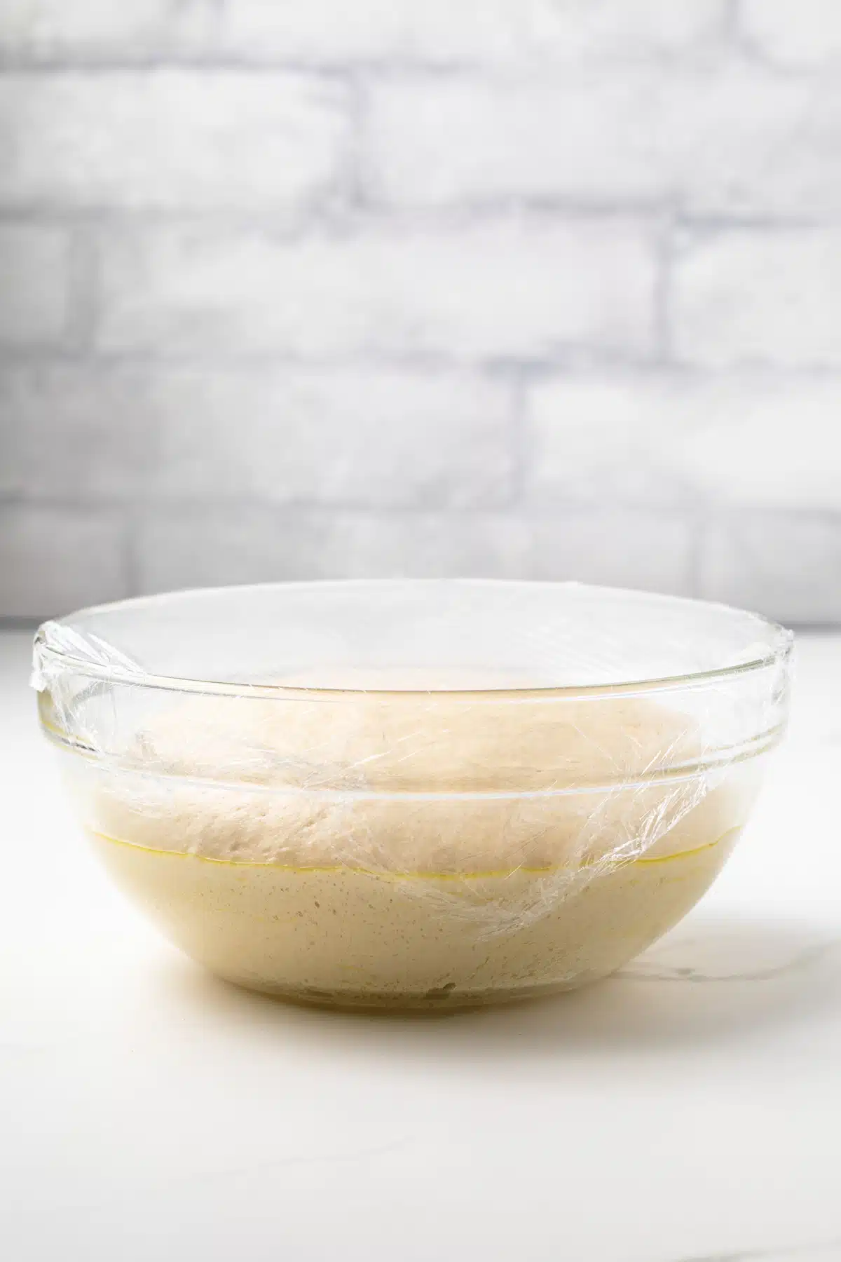 Dough risen in a glass bowl.