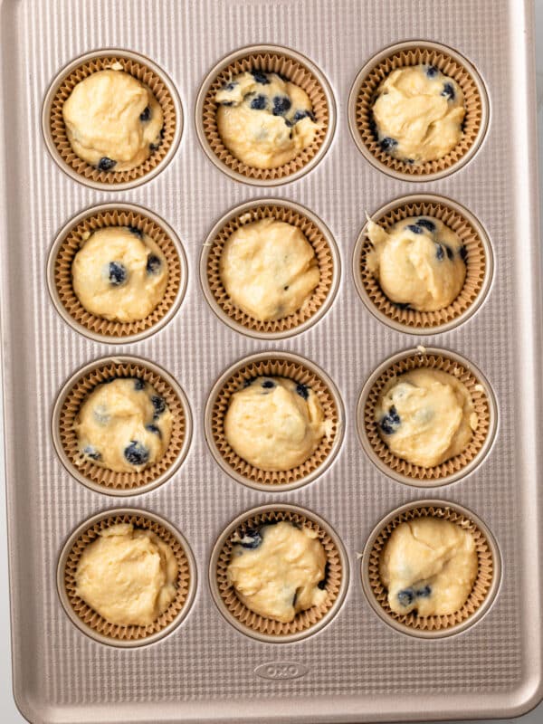 Unbaked lemon blueberry cupcakes in a muffin pan.