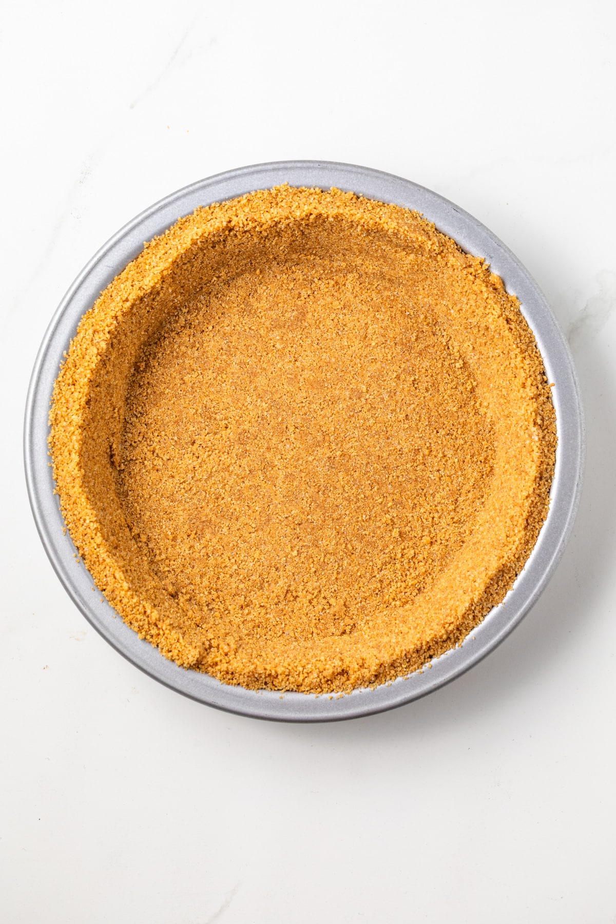 Graham cracker crust in a metal pie pan.