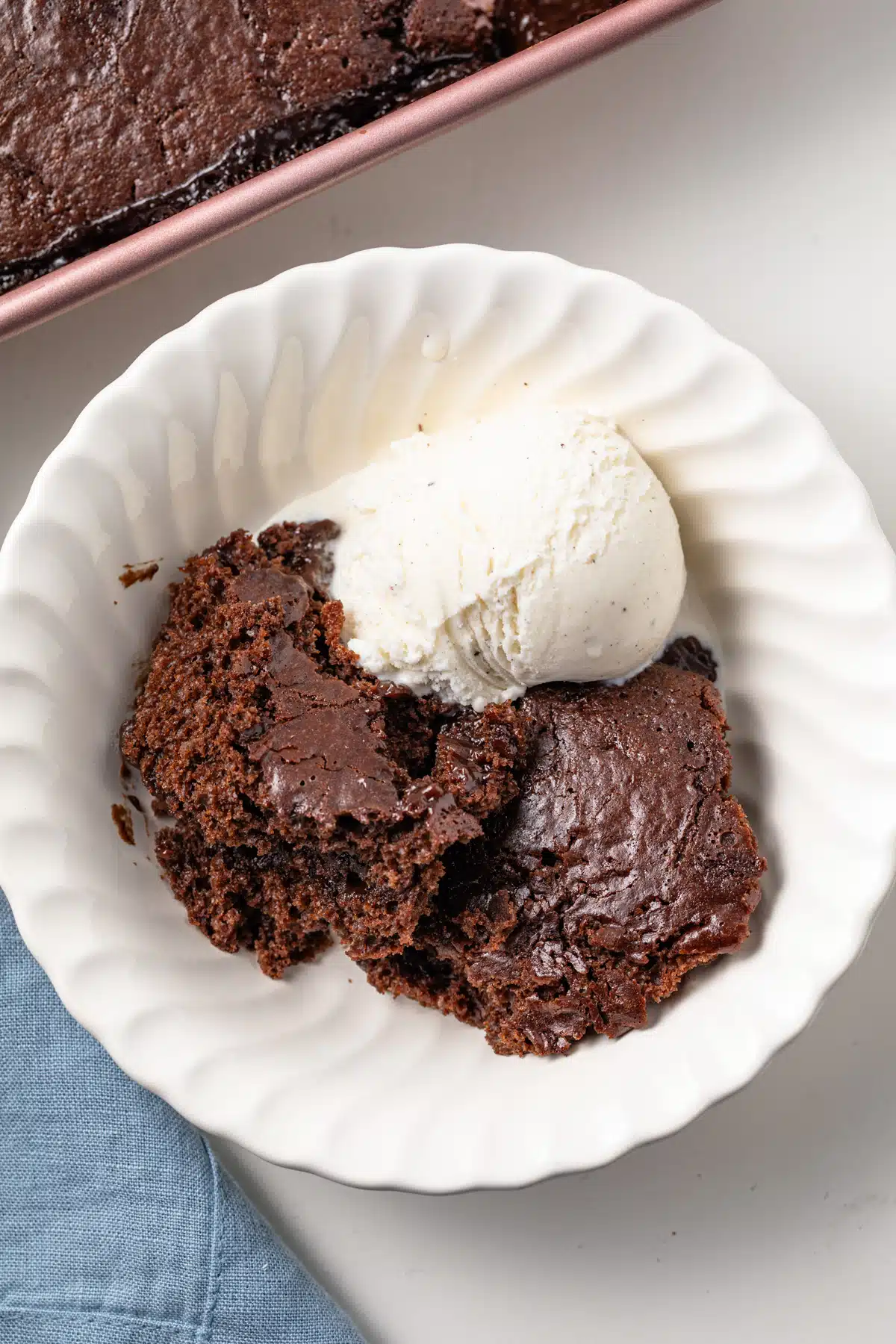 An overhead view of chocolate pudding cake in a bowl with a scoop of ice cream.