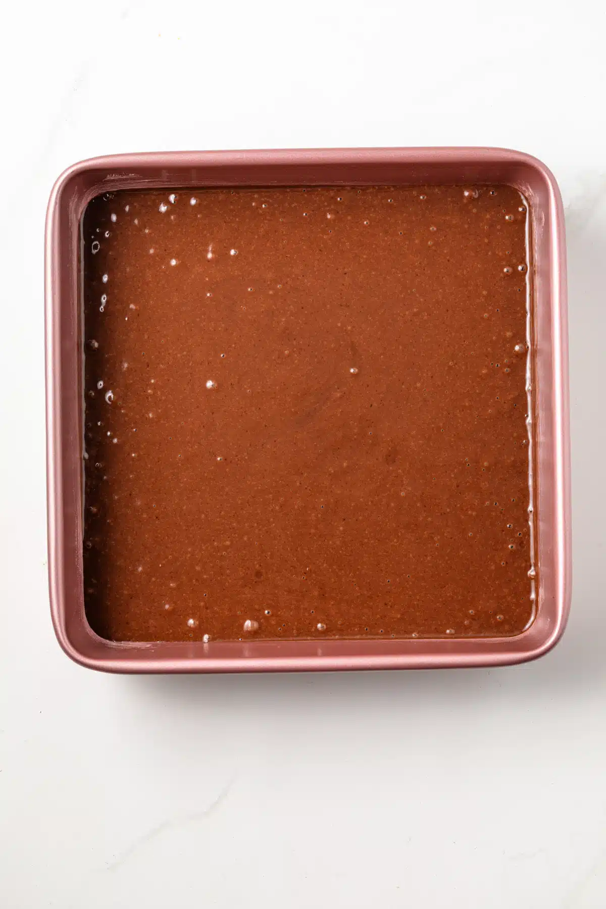 An overhead view of chocolate pudding cake batter in a square pan.